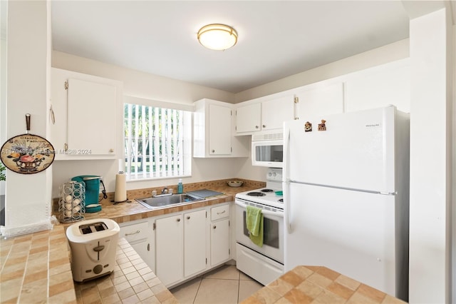 kitchen with light tile patterned floors, white appliances, white cabinetry, and sink