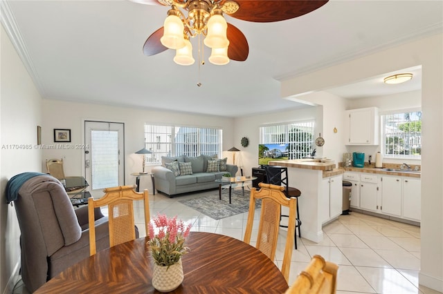 dining space featuring ceiling fan, light tile patterned floors, sink, and ornamental molding