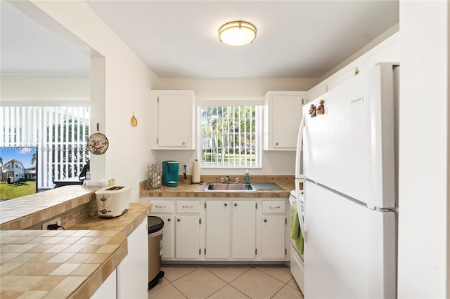 kitchen featuring white cabinetry, tile counters, sink, white appliances, and light tile patterned floors