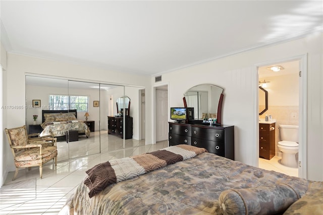 bedroom with light tile patterned floors, connected bathroom, a closet, and ornamental molding