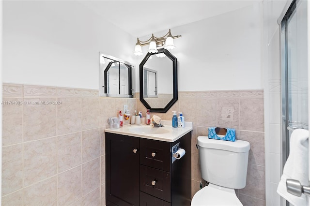 bathroom featuring vanity, toilet, and tile walls