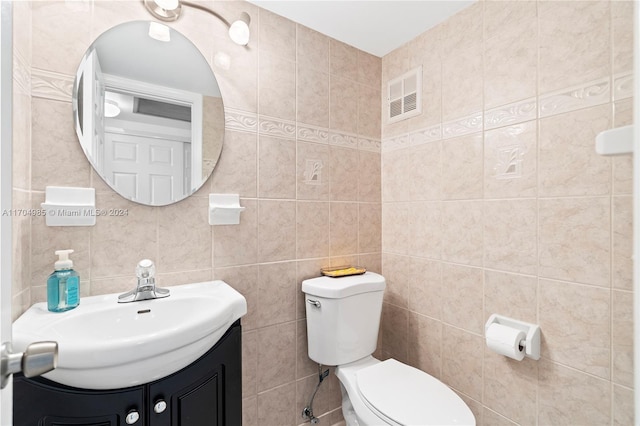 bathroom featuring vanity, tasteful backsplash, toilet, and tile walls