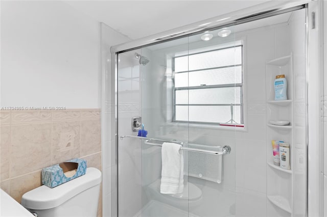 bathroom featuring an enclosed shower, tile walls, and toilet