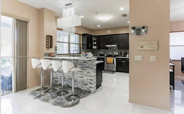 kitchen featuring a kitchen breakfast bar, sink, decorative backsplash, stainless steel electric range oven, and kitchen peninsula