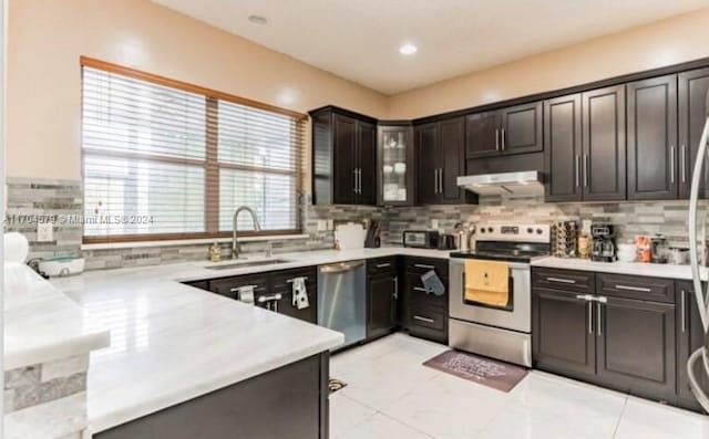 kitchen with tasteful backsplash, sink, dark brown cabinets, and appliances with stainless steel finishes