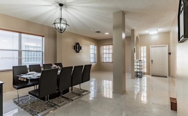 dining space with a notable chandelier, a healthy amount of sunlight, and a textured ceiling