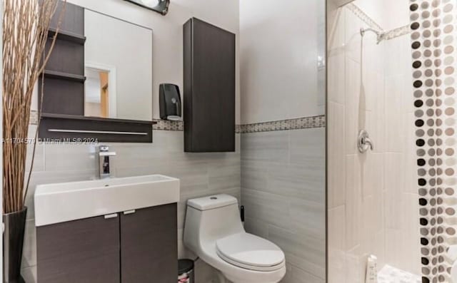 bathroom featuring a tile shower, vanity, tile walls, and toilet