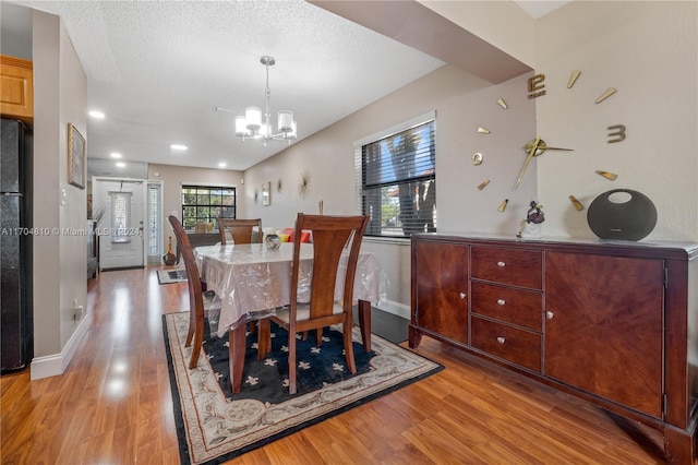 dining room with a chandelier, a textured ceiling, and light hardwood / wood-style floors