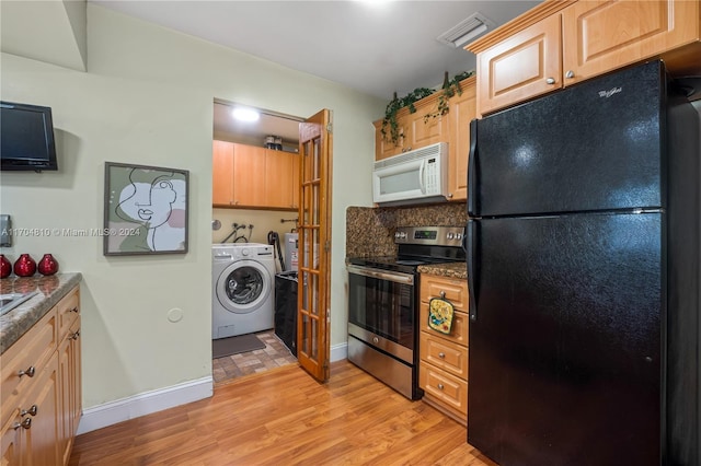 kitchen featuring stainless steel electric range oven, backsplash, black refrigerator, light brown cabinetry, and light wood-type flooring