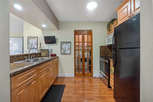 kitchen featuring sink, dark stone counters, stainless steel electric stove, black refrigerator, and light wood-type flooring