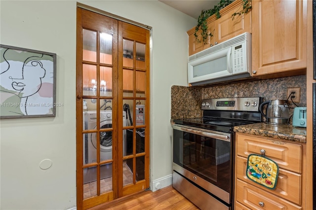 kitchen with backsplash, dark stone counters, electric stove, light hardwood / wood-style flooring, and washer / dryer