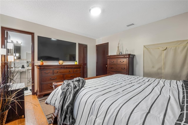 bedroom featuring a closet, light hardwood / wood-style flooring, and a textured ceiling