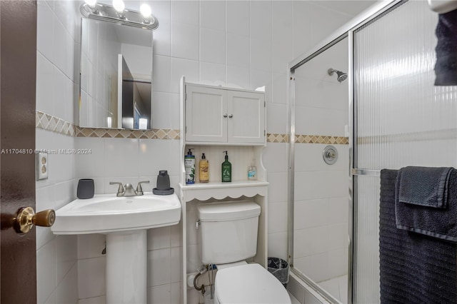 bathroom featuring toilet, tile walls, and a shower with shower door