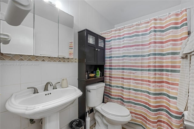 bathroom with backsplash, sink, toilet, and tile walls