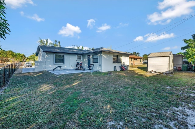 back of property featuring a yard, a patio, and a shed