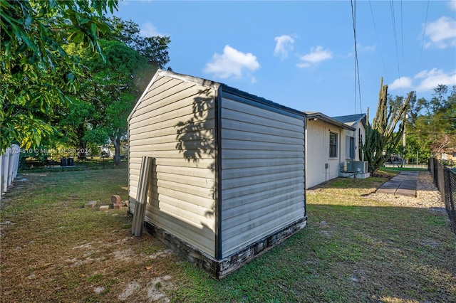 view of outdoor structure featuring central AC and a lawn