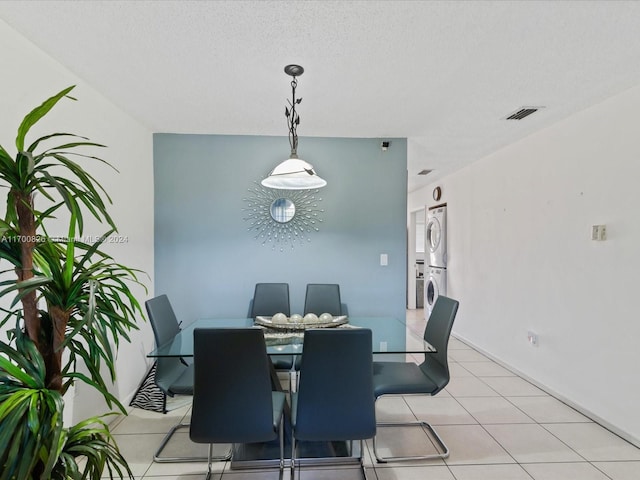 dining space featuring stacked washer / dryer, a textured ceiling, and an inviting chandelier