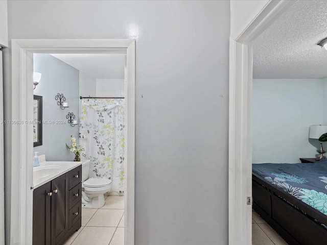 bathroom featuring toilet, vanity, a textured ceiling, and tile patterned floors