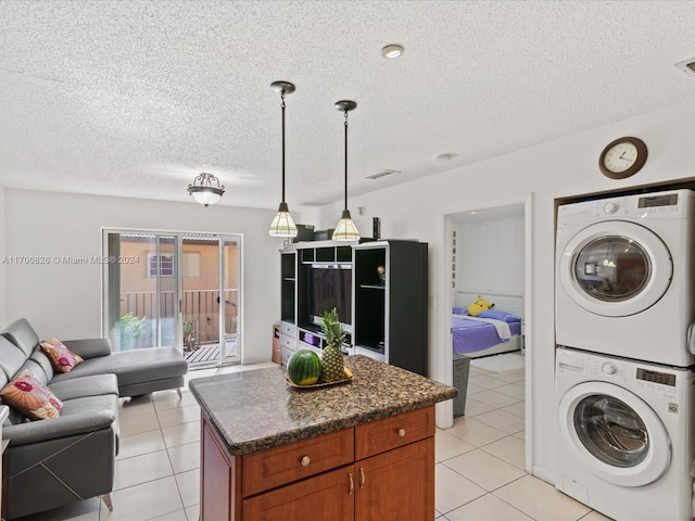 washroom with a textured ceiling, light tile patterned floors, and stacked washer / drying machine