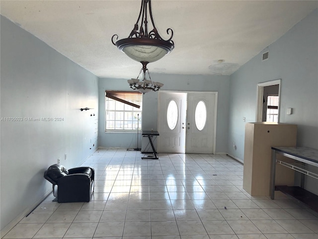 tiled foyer with a chandelier