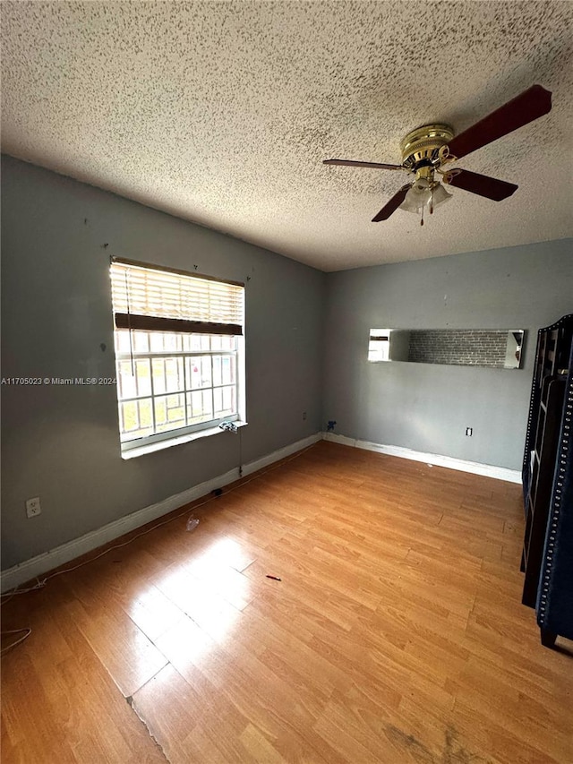 spare room featuring ceiling fan, light hardwood / wood-style flooring, and a textured ceiling