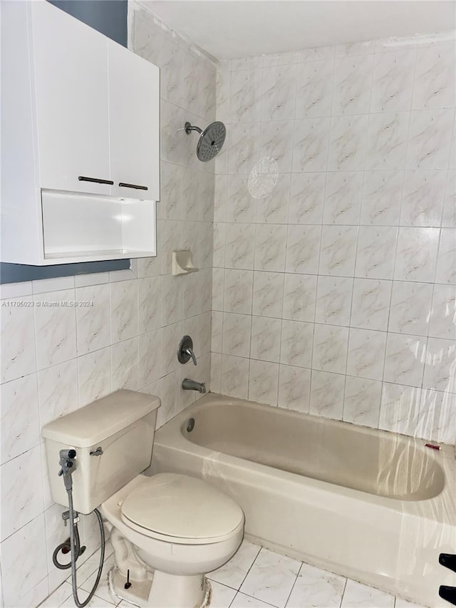 bathroom with toilet, tile walls, and tiled shower / bath