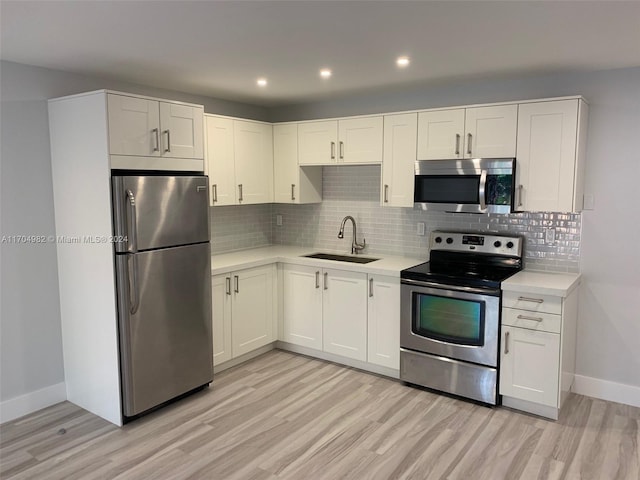 kitchen featuring sink, white cabinets, stainless steel appliances, and light wood-type flooring