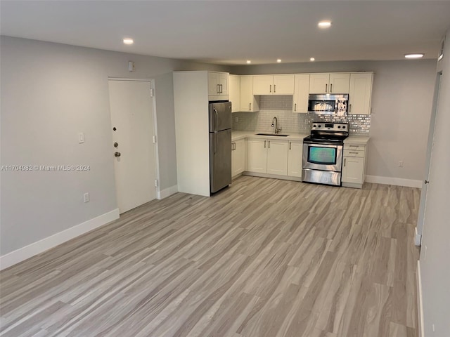 kitchen featuring backsplash, white cabinets, sink, light hardwood / wood-style floors, and stainless steel appliances