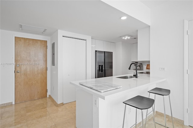 kitchen featuring white cabinetry, kitchen peninsula, stainless steel fridge, and sink