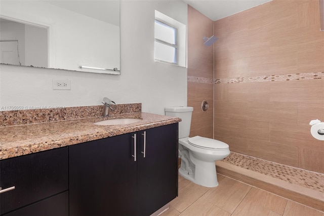 bathroom featuring tiled shower, vanity, and toilet