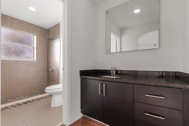 bathroom with a tile shower, vanity, toilet, and tile patterned floors