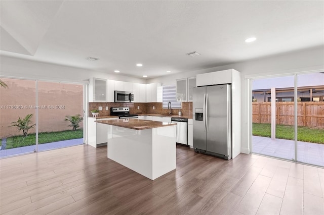 kitchen featuring a center island, dark wood-type flooring, decorative backsplash, white cabinetry, and stainless steel appliances