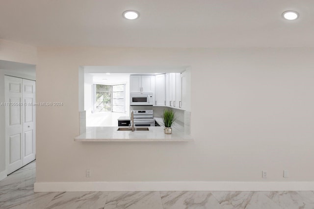 kitchen featuring white cabinets, kitchen peninsula, white appliances, and sink