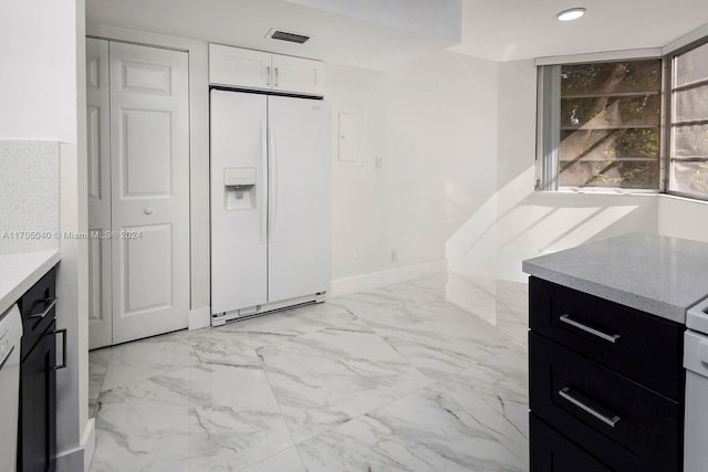 kitchen featuring white cabinetry and white refrigerator with ice dispenser