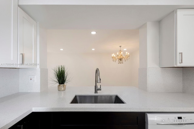 kitchen featuring white dishwasher, light stone counters, white cabinetry, and sink