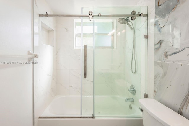 bathroom featuring toilet and combined bath / shower with glass door