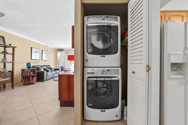 laundry room featuring light tile patterned floors, a textured ceiling, stacked washing maching and dryer, and crown molding