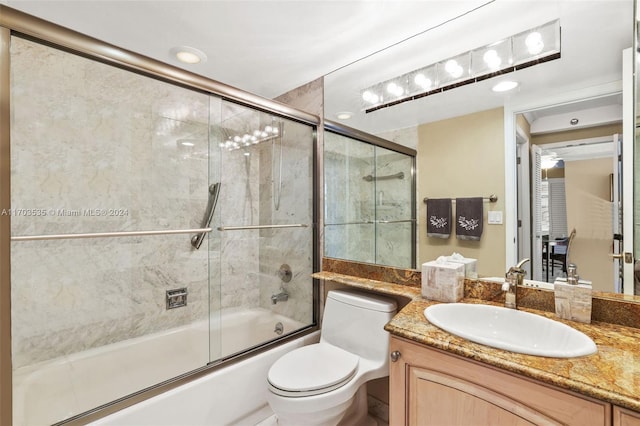 full bathroom featuring shower / bath combination with glass door, vanity, and toilet