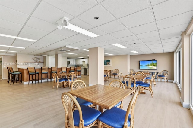 dining area featuring a drop ceiling and light wood-type flooring