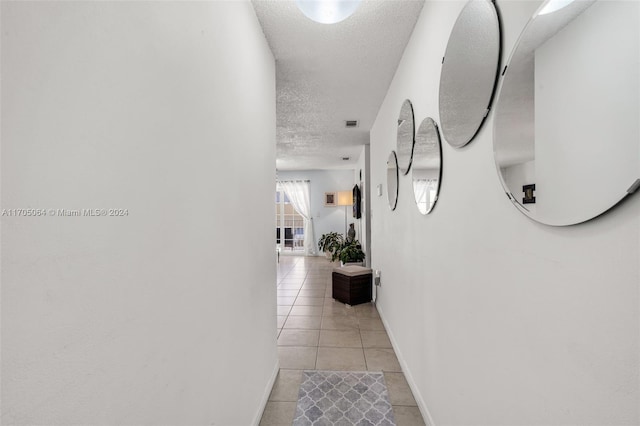 hall with light tile patterned floors and a textured ceiling