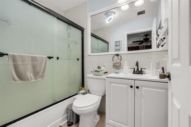 full bathroom with decorative backsplash, vanity, bath / shower combo with glass door, and tile walls