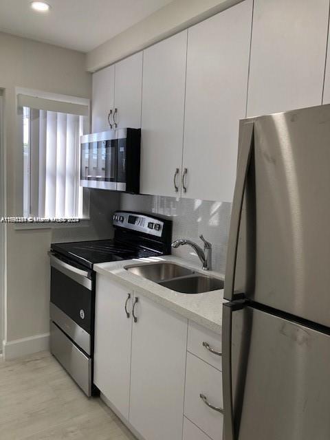 kitchen featuring light hardwood / wood-style floors, sink, white cabinetry, and stainless steel appliances