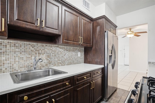 kitchen with decorative backsplash, dark brown cabinetry, ceiling fan, sink, and stainless steel fridge with ice dispenser