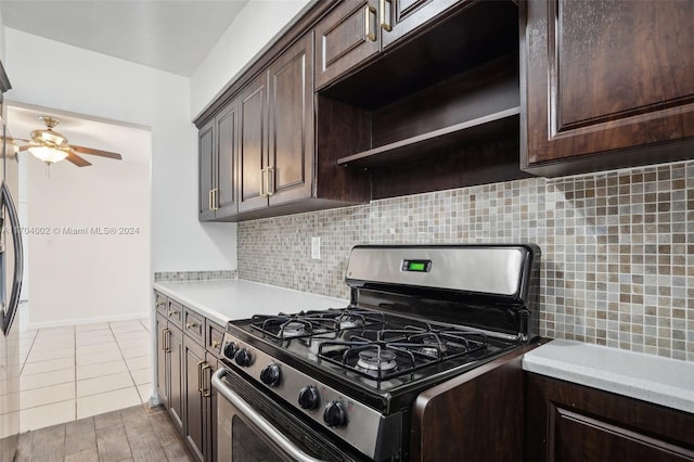 kitchen featuring backsplash, stainless steel gas range, dark brown cabinets, ceiling fan, and light tile patterned floors