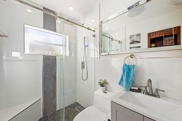 bathroom featuring a shower with door, vanity, and toilet