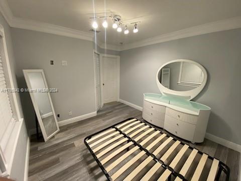 bedroom featuring crown molding and dark wood-type flooring