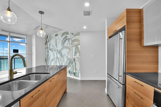 kitchen with pendant lighting, wall oven, sink, and stainless steel refrigerator