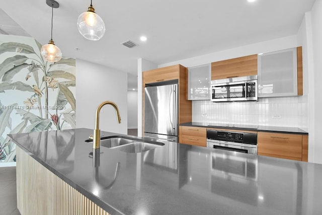 kitchen with tile patterned floors, sink, appliances with stainless steel finishes, tasteful backsplash, and decorative light fixtures