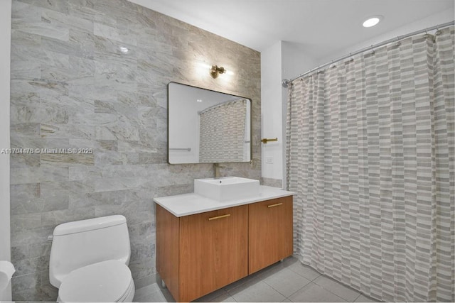 bathroom featuring vanity, tile patterned flooring, toilet, tile walls, and walk in shower