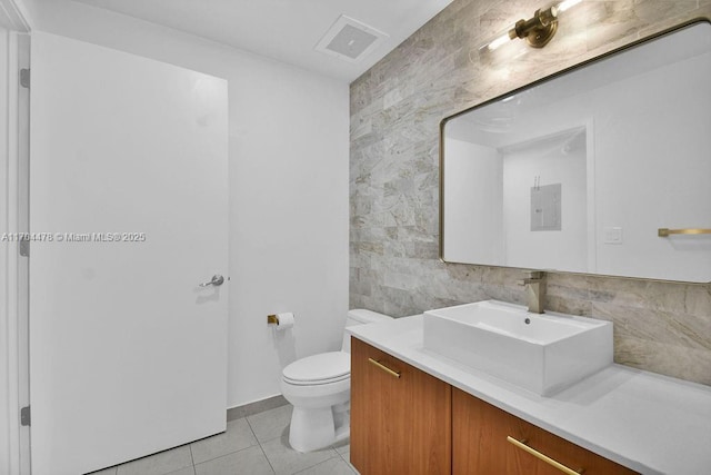 bathroom with tile patterned flooring, vanity, tile walls, and toilet